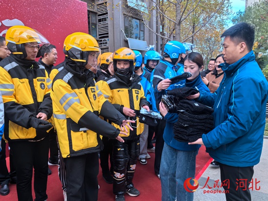 與會嘉賓向出席活動的騎手贈予手套和帽子。人民網(wǎng) 商帆攝