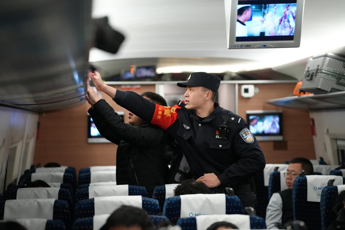 G7818次列車乘警在車廂里面幫助旅客放置行李箱。賈義涵攝